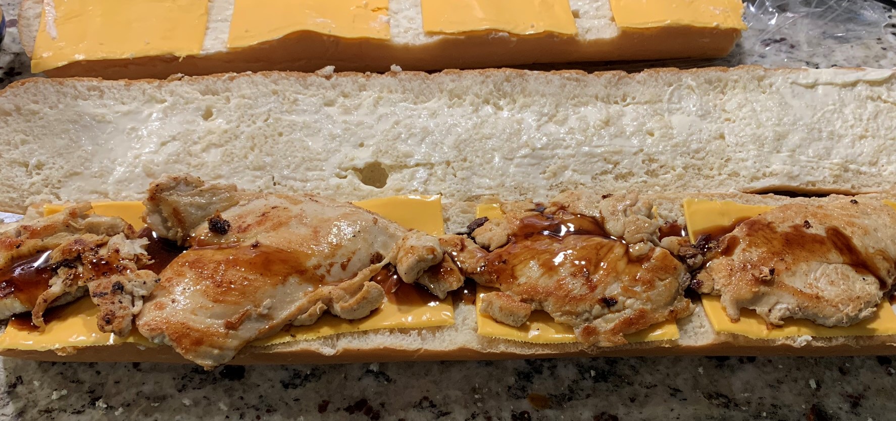 Chicken thigh clam sauce and Hoisin sauce on a long French bread with yellow American cheese